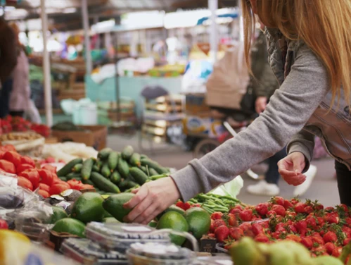 vegetable stand with woman selecting cucumber