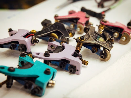 An up close up picture of coil tattooing machines on a table.