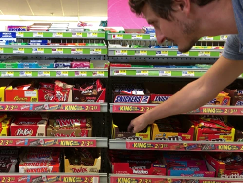 man choosing candy in a convenience store aisle
