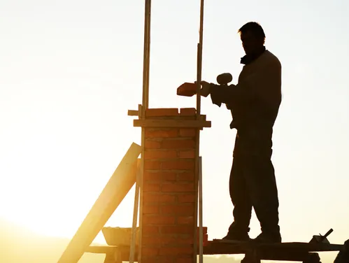 Construction Worker building a new house at sunset