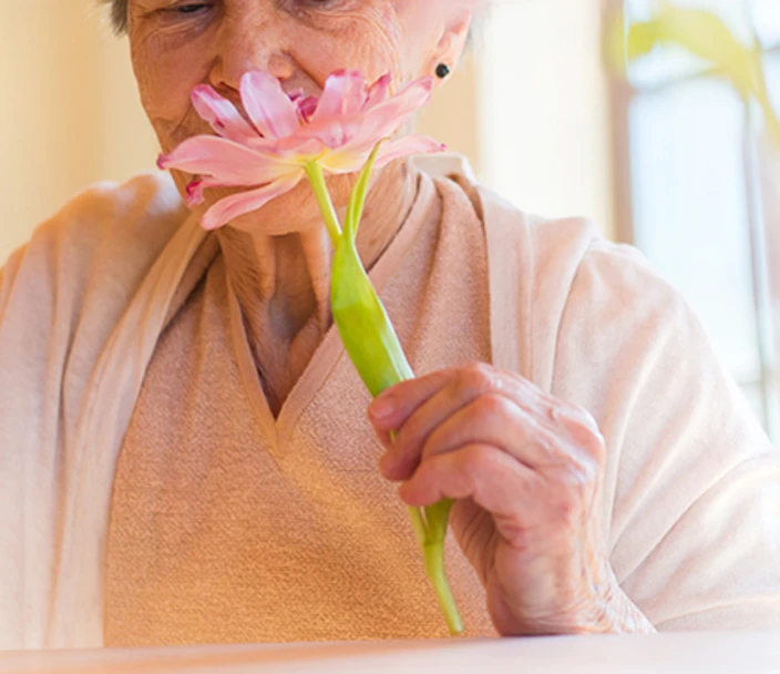 Beautiful older woman holding a pink flower