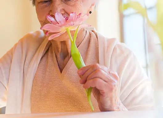 Beautiful older woman holding a pink flower