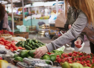 vegetable stand with woman selecting cucumber