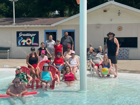 Group of elderly adults sitting in a shallow pool area